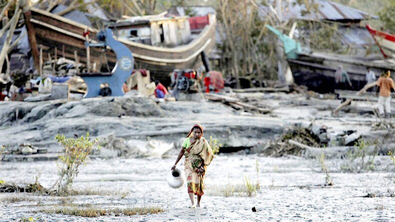 Una donna cammina nel fango e tra le macerie dopo che un ciclone ha colpito un villaggio del Bangladesh nel novembre 2007